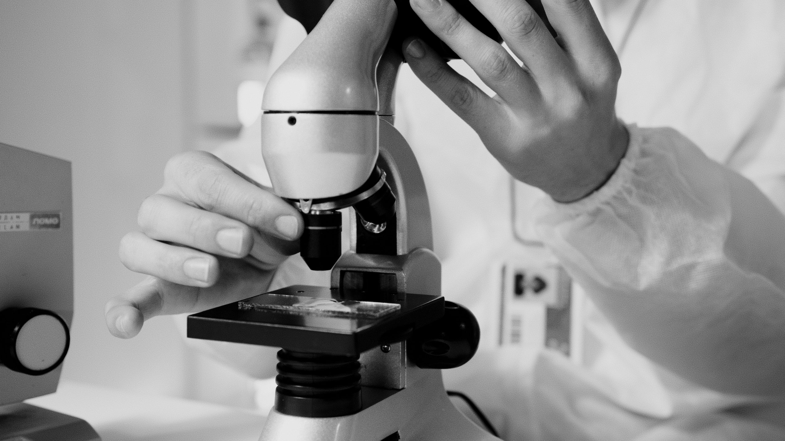 Scientist using a microscope in a laboratory, representing cancer research and experimental precision.